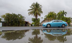 A vehicle passes puddles of water on the side of the road in Cairns, Queensland, Australia.