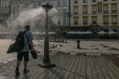 A man stands under a municipal water spray station in a Krawkow square