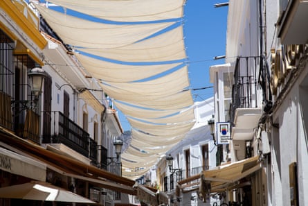White sun shade sails hang over the houses in a street in Spain