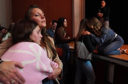 A woman kneels on stage to pray over another woman
