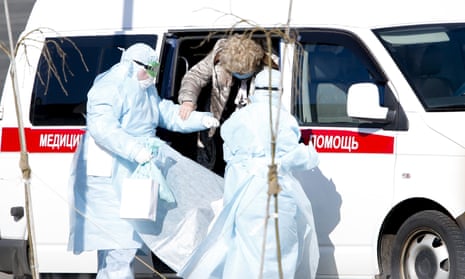 Paramedics, wearing protective suits and carrying suspected coronavirus patients, are seen near an ambulance as they arrived at the Kommunarka Hospital in Moscow, Russia.