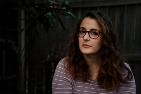 A photo of Ellen Sautelle, who has endometriosis. She has wavy auburn-brown hair and is wearing glasses with a brown square frame and a mauve and white striped top