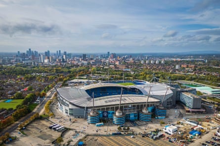 Aerial view of Manchester’s Etihad Stadium with the city skyline behind it