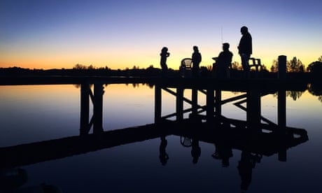 Silhouette of people standing by a lake
