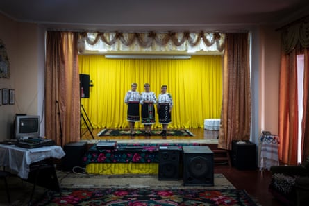Three women in tradition costumes on a small stage