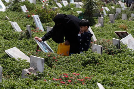 A Yemeni woman and her grandson in 2021 visit the grave of her late son in Sana’a.