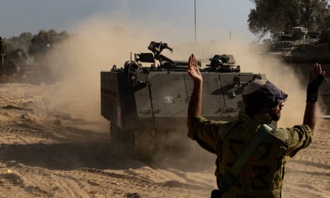An Israeli soldier guides an armoured personnel carrier in southern Israel on Saturday amid massed troops at the border with Gaza