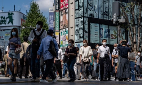 people walk across a street in tokyo