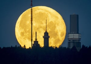 The full moon sets behind the telecommunication devices on top of the Feldberg mountain near Frankfurt, Germany