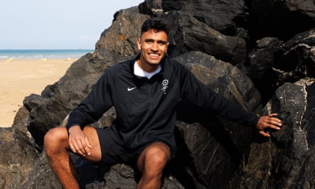 Farzad Mansouri sitting on some rocks by a beach.