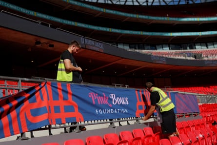 Workers putting up banners advertising the Pink Bows Foundation at Wembey Stadium