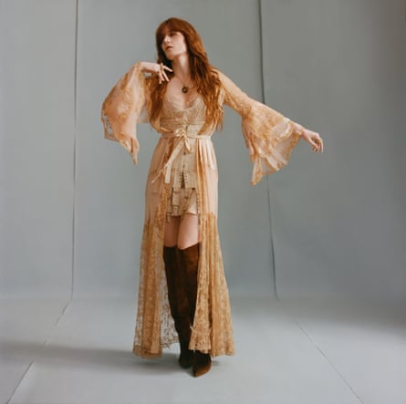 Florence Welch wearing a flowing peach outfit and long, dark-brown boots