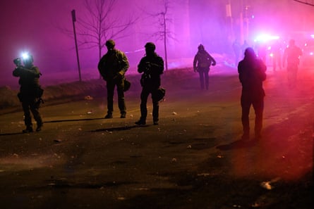 people in tactical gear walk on a street outside