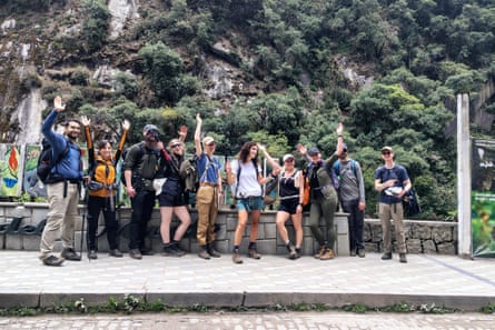 A group of tourists waves while leaving on foot due to a protest by residents in Machu Picchu