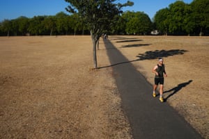 A person jogs on a path between dry grass in Victoria Park, east London