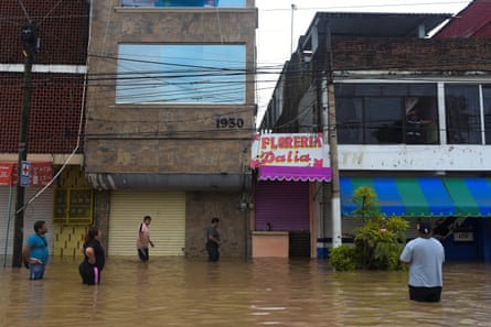People wade through a flooded street after torrential rains that caused an overflow of rivers in the city of Poza Rica, Mexico