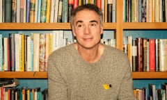 Greg Wise sitting in front of a book case