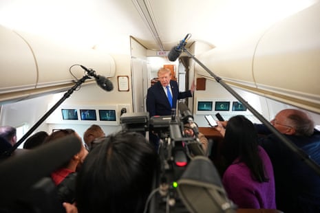 Trump gestures while speaking to reporters with microphones aboard Air Force One