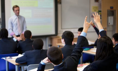 A teacher speaking to a class of pupils sitting at desks
