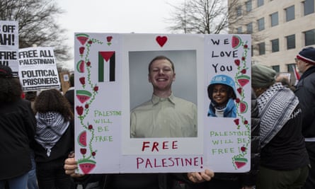 Demonstrator holding a placard featuring an image of Aaron Bushnell at a protest in Washington