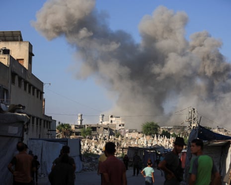 Palestinans look on as smoke rises following an explosion during an Israeli operation, in Gaza City.