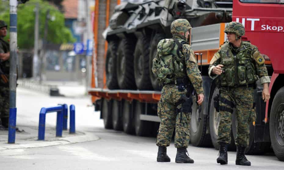 Police officers stand next to a lorry loaded with a damaged armoured personnel carrier in the northern Macedonian town of Kumanovo.