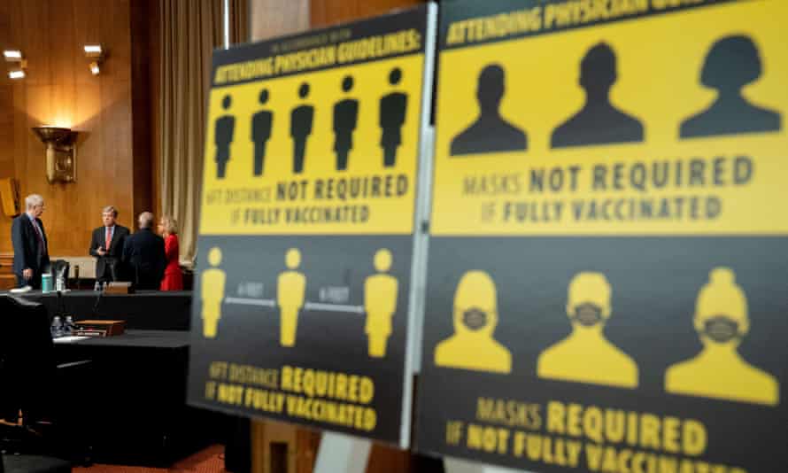 Francis Collins, at far left, waits for a May congressional hearing next to signs requiring masks if not vaccinated against Covid-19.