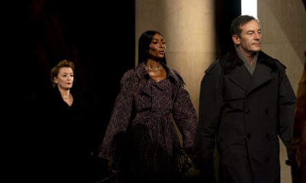 Lesley Manville, Naomi Campbell and Jason Isaacs on the runway wearing thick, darkly-coloured coats
