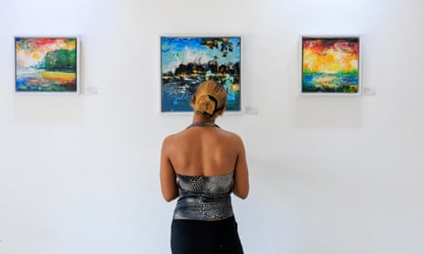 A woman stands and contemplates a painting on a gallery wall.