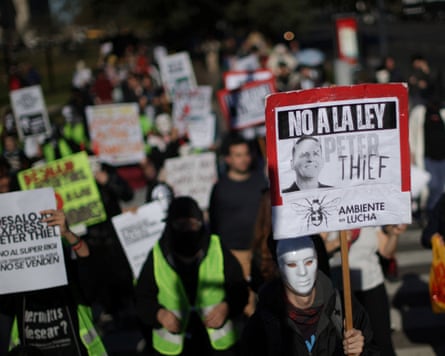 Protesters holding placards that say ‘Peter Thief’ and wearing white masks