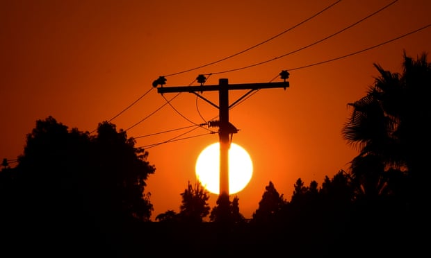The sun sets behind power lines during a heatwave in Los Angeles.