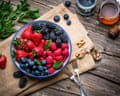 Bowl of assorted colorful freshly picked berry fruits on rustic picnic table