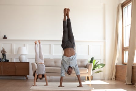 father and daughter do a handstand on mat inside living room