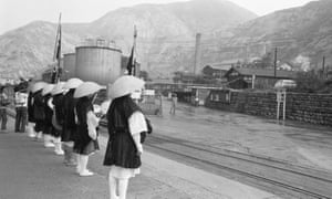 A row of monks standing outside an industrial plant