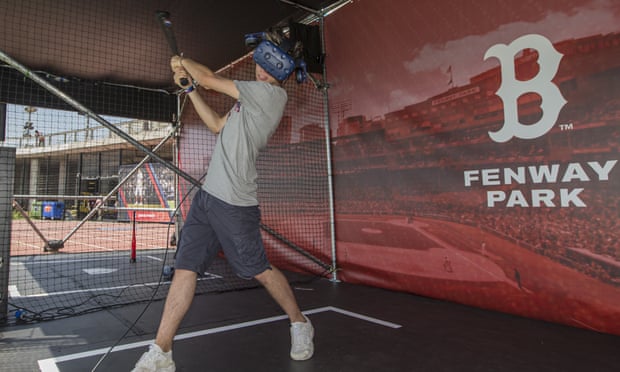 A Boston Red Sox fan practises his batting swing virtually against a photographic background of Fenway Park.