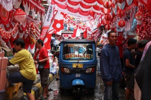 A rickshaw taxi drives through a highly decorated market in Jakarta