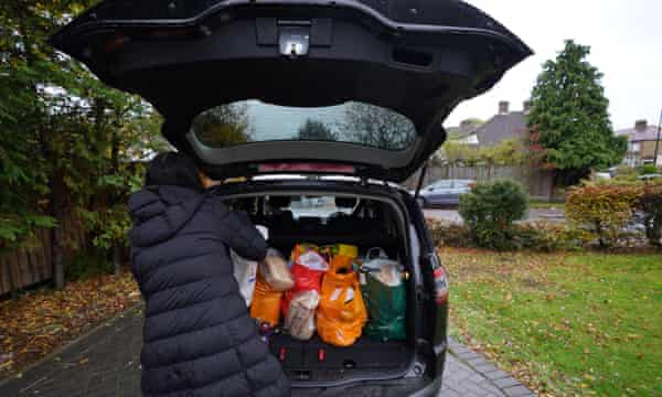 A volunteer loads food parcels into a car in London in October 2020