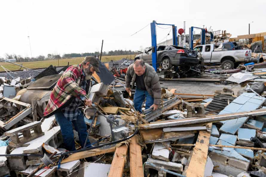 Two men dig through debris left when a tornado destroyed an automobile repair shop.
