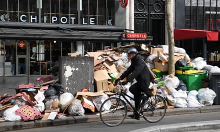 A cyclist riding past piles of rubbish in Paris’s 2nd district.