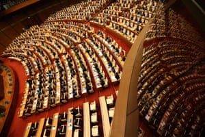 Rows of people in a large auditorium with red carpet