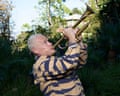 The musician Flea playing a trumpet surrounded by foliage
