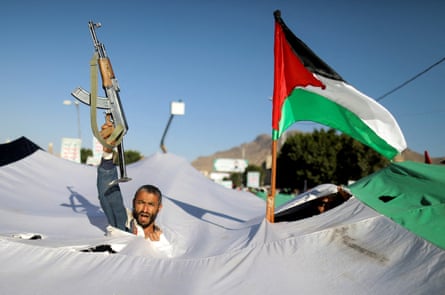A protester holds up a gun next to the Palestinian flag during a demonstration in solidarity with Palestinians in Gaza, in San’aa, Yemen.