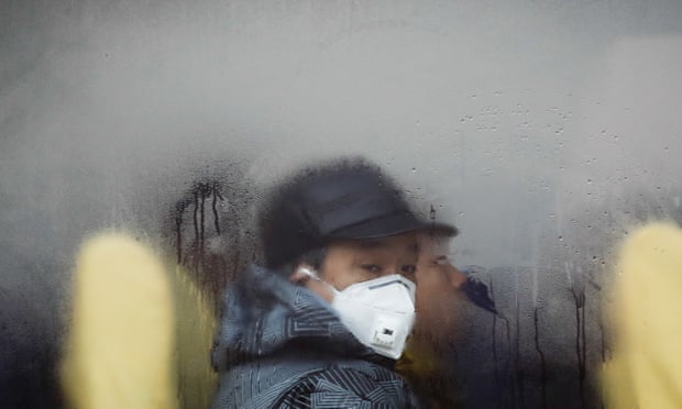 A man wearing a mask looks out from a bus in Beijing as the city is blanketed by smog, Dec 2016