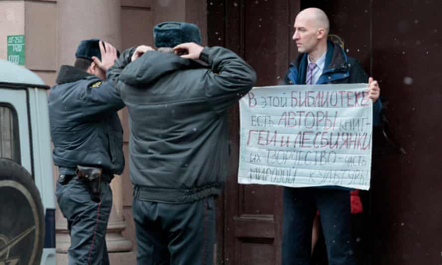 Policemen approach to check a passport of a gay rights activist standing in individual picket in St.Petersburg, Russia, Wednesday, April 4, 2012. His poster reads: “In this library there are also books by gay and lesbian writers. Their works are a part of the world culture”.