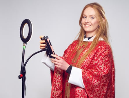 Priest in red robes standing in front of a ring light on a tripod