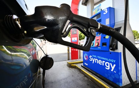 A gasoline nozzle pumps fuel into a vehicle at a gas station.