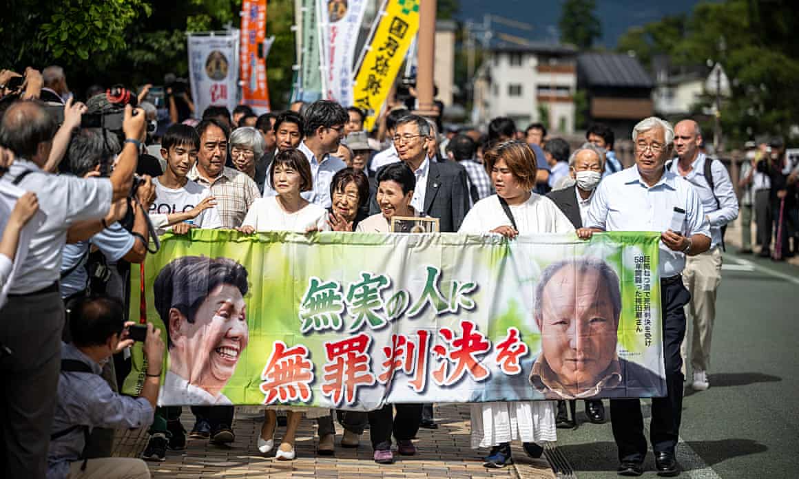 Crowd of demonstrators holding up a banner reading ‘innocent man, not guilty verdict’ in Japanese