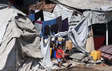 A child carries a broom at a camp for displaced Palestinians in Gaza City.