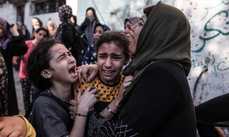 Relatives of Palestinians, who died in the Israeli airstrikes, mourn around rubble of buildings