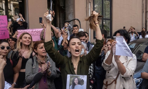 A woman cuts off her ponytail in front of Iran's embassy in Istanbul, Turkey